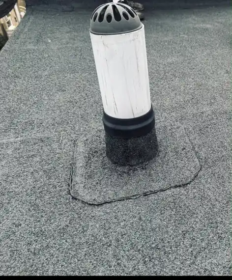 Roof vent sealed into a new mineral felt cap sheet on a flat roof