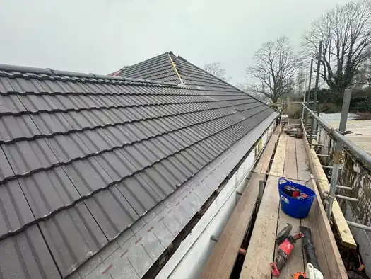 New grey tile roof seen from the scaffold at the eaves