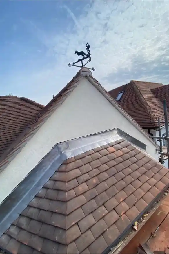 Plain clay tile roof with lead-dressed gable and weathervane
