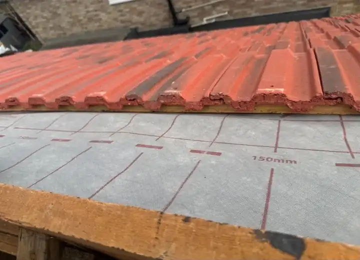 Red tiles going on over breathable membrane at the eaves