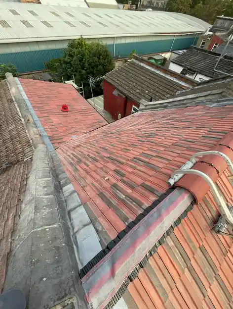 Red tile roof with lead flashing along the wall abutment and a bedded ridge