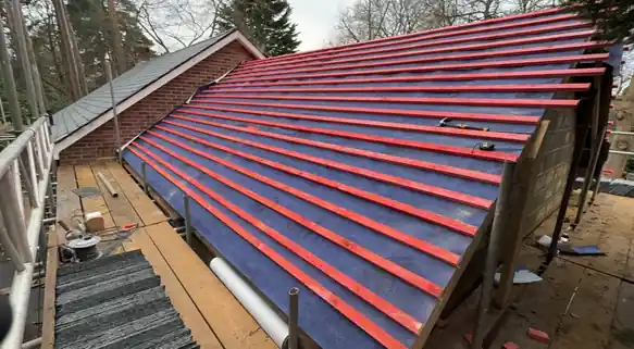 Roof slope felted and battened ready for new tiles, seen from the scaffold