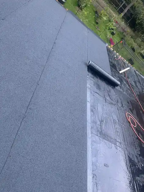 Mineral cap sheet rolled out over a torch-on flat roof
