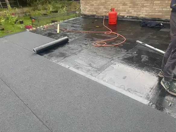 Torch-on felt flat roof installation in progress