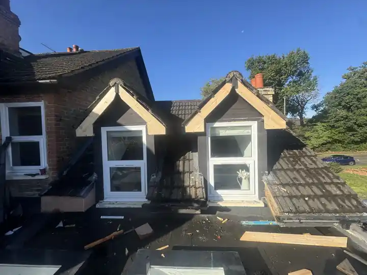 Two dormers rebuilt with new timber frames while the roof tiles around them are stripped